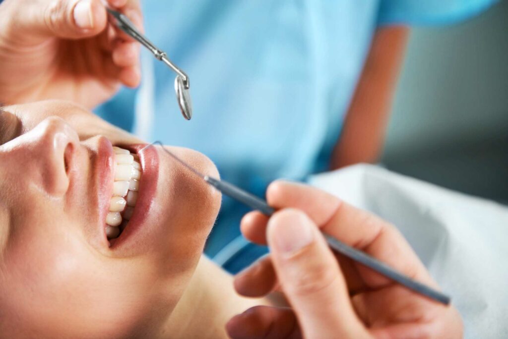 photo of a dentist using dental tools on a female patient's mouth for a regular dental checkup