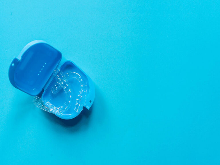 Invisalign aligners in a portable case on a blue background