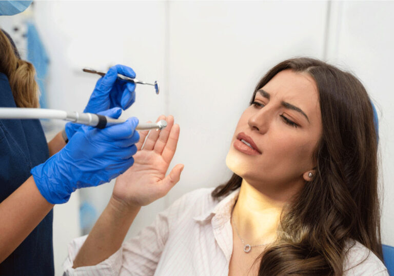 female patient holding her hand up in front of dental tools